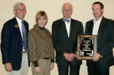 Group of four holding a plaque